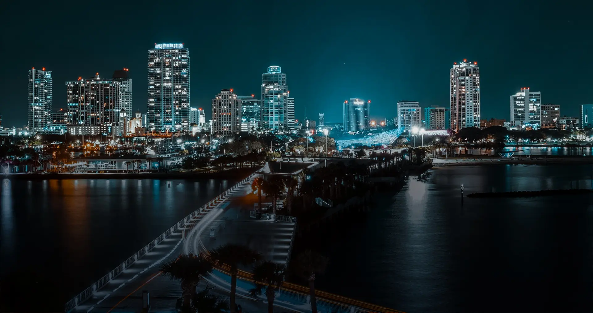 Panoramic night view of the illuminated city skyline and waterfront, representing the local service area of a professional Roofing Company in St Petersburg.