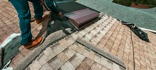 A technician from a Roofing Company in Tampa installing flashing around a roof vent to ensure a watertight seal on a residential shingle roof.