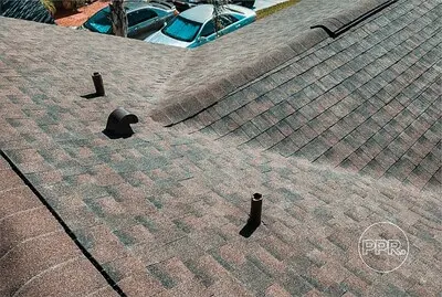 Asphalt shingle roof with proper ventilation pipes, showcasing best practices to protect and preserve roofing against heat and moisture damage.