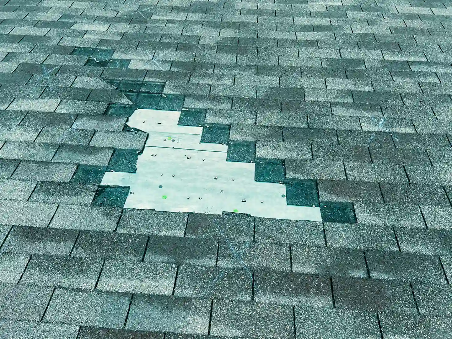 Missing asphalt shingles exposing roof underlayment, highlighting the importance to protect and preserve roofing from weather damage