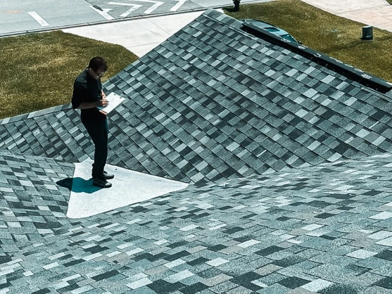 Professional inspector on a shingle roof taking notes for expert roof repair services.