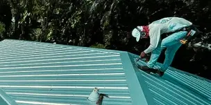 Close-up of a caulking gun applying waterproof sealant to the panel joints to stop leaks, a key step in metal roof repair service.