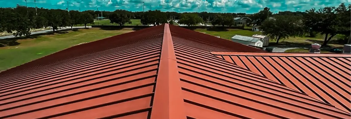 Panoramic view of a completed metal roof repair service project featuring a durable red standing seam roof system in a park setting.