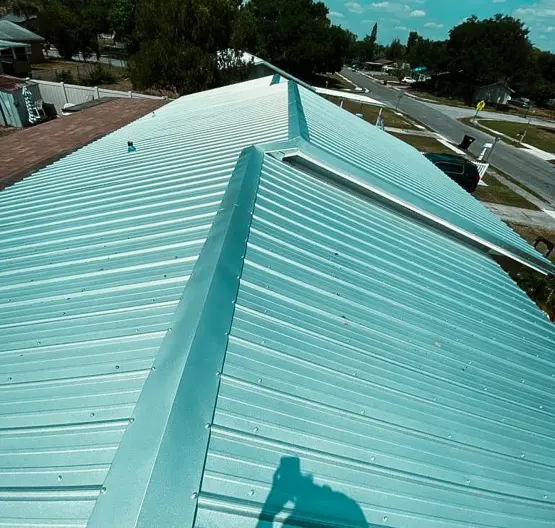High-angle overview of a light green standing seam roof system, showcasing the quality finish of a professional metal roof repair service.