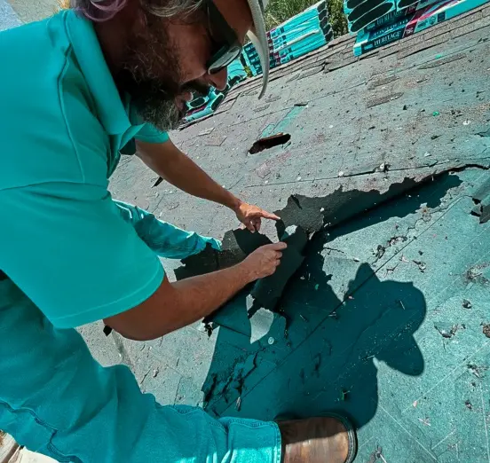A professional roofer removing old, damaged underlayment from a roof deck to prepare the surface for high quality new roof services.