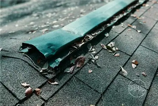 A close-up of a damaged roof vent with torn flashing and debris, a common source of leaks that Protect Preserve Roofing inspects and repairs.