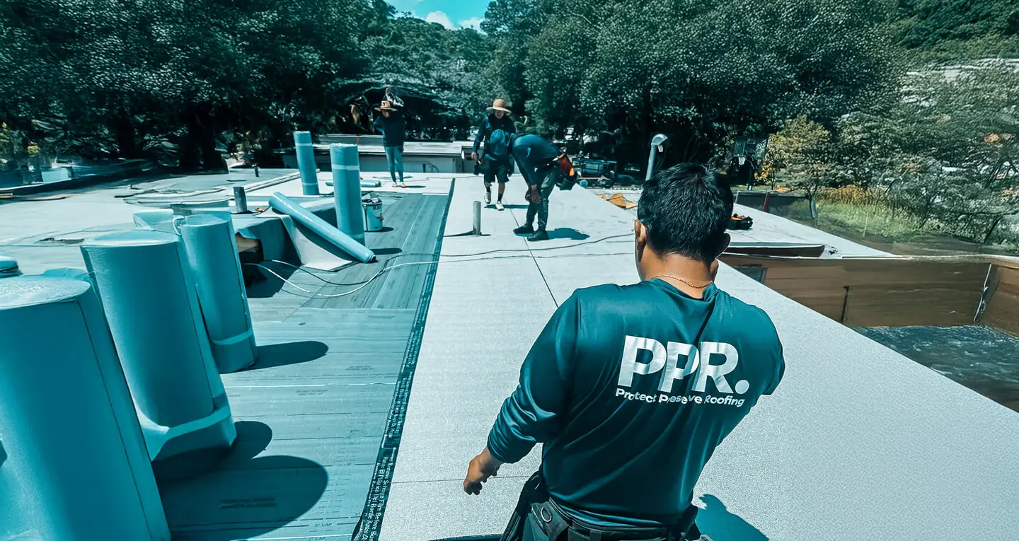 Protect Preserve Roofing team installing a flat roof with rolls of material and equipment under a sunny sky.