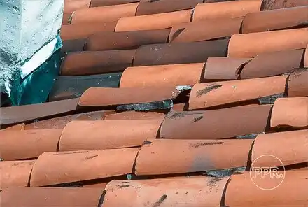 A close-up of a damaged tile roof with multiple broken and misaligned tiles, a common issue that Protect Preserve Roofing can repair.