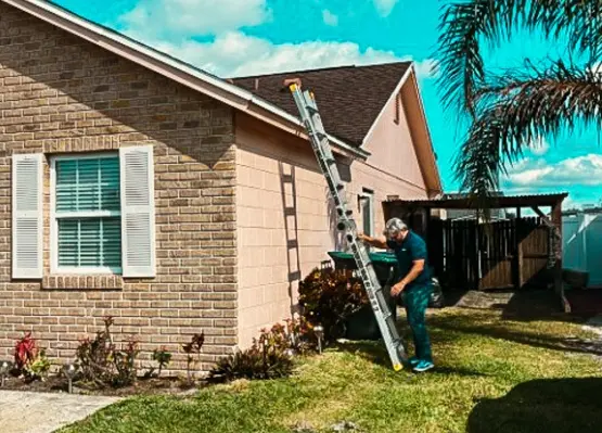 Man inspecting a residential roof using a ladder outside a house in Florida, showing the importance to schedule-a-roof inspection-in-florida for home maintenance and safety.