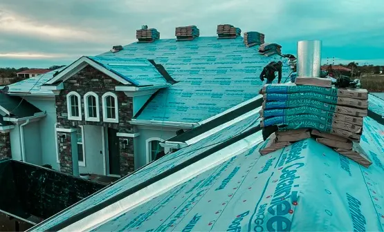 A residential home with a roof fully covered in blue CertainTeed Roof Runner underlayment, and stacks of CertainTeed Landmark shingles ready for installation by Protect Preserve Roofing.