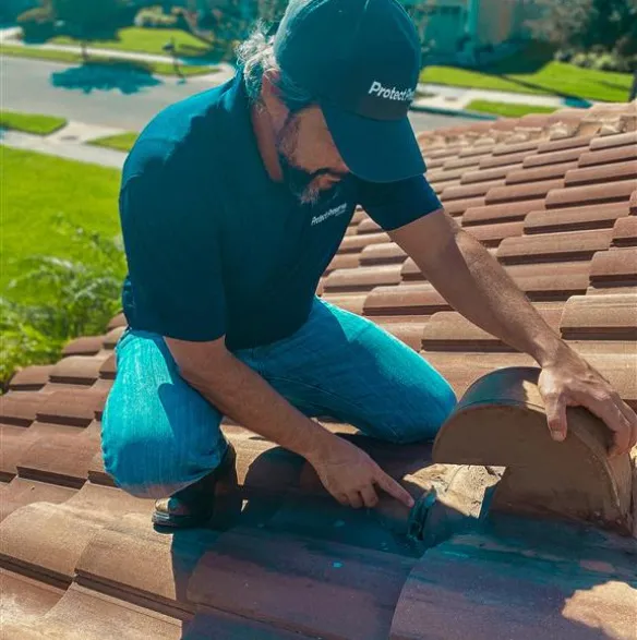 Professional roofer inspecting a vent on a clay tile roof, demonstrating expert tile roof repair service.