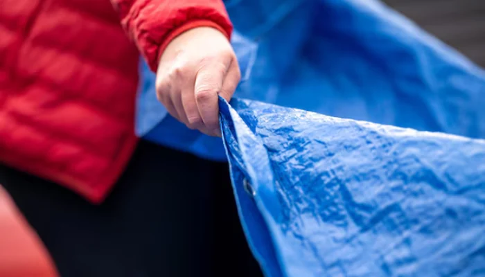 A person holding a blue tarp to represent the keyword person holding a blue tarp.