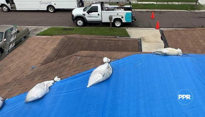 Blue tarp secured with sandbags on a roof after storm damage.