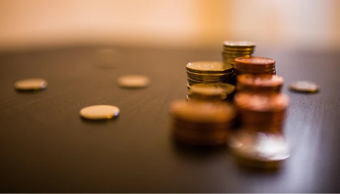 Coins stacked and spaced out on a table to represent the keyword tarp the roof value.