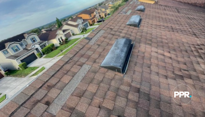 Shingle roof with visible storm damage, including missing shingles and exposed underlayment.