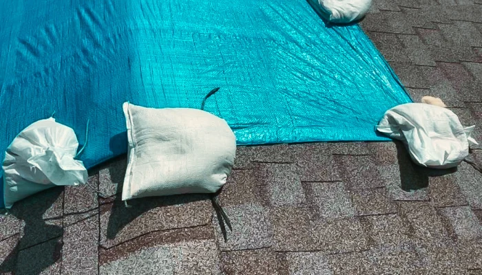 Roof with a blue tarp secured with sandbags to represent the keyword blue tarp a roof with sandbags.