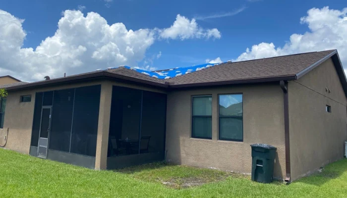 Blue tarp installed on a house during the day to represent the keyword blue tarp during the day.