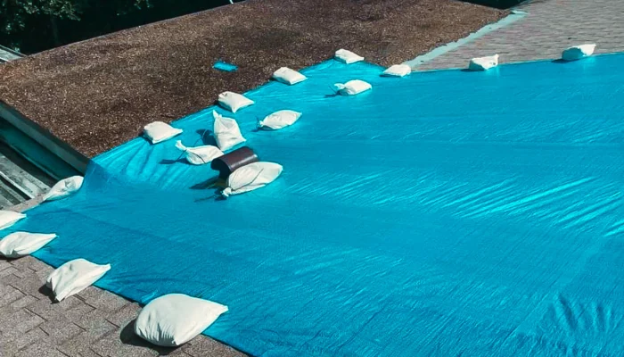 Blue tarp installed on a tile roof with sandbags to represent the keyword blue tarping a roof.