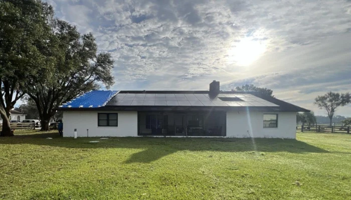 Roof partially covered with a blue tarp with strong sun in the background to represent keyword do blue tarps block uv or just create shade.