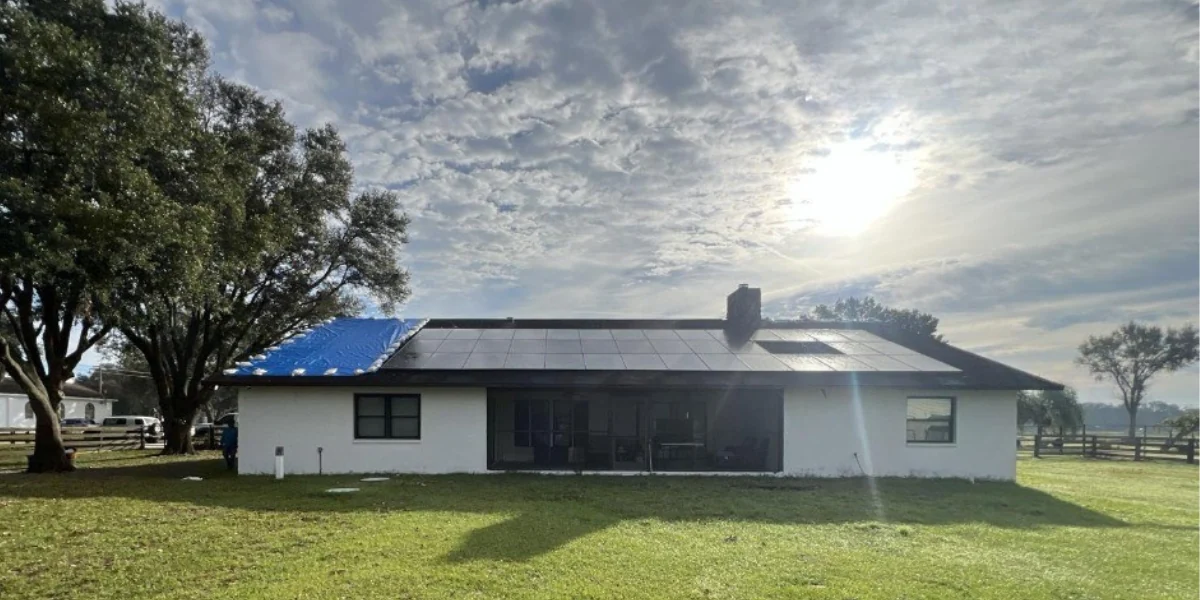 Roof partially covered with a blue tarp with strong sun in the background to represent keyword do blue tarps block uv.