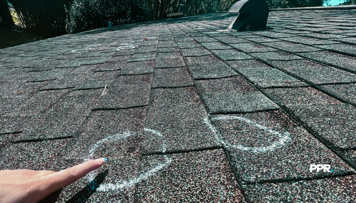 Shingle roof with storm damage marked using chalk circles to highlight impacted areas.