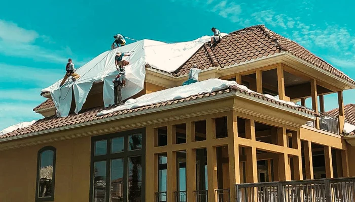 Team installing tarp on a roof to represent the keyword shrink wrap vs blue tarps crew.