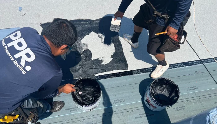 Two men working on the roof, tarping to represent the keyword tarping a roof.