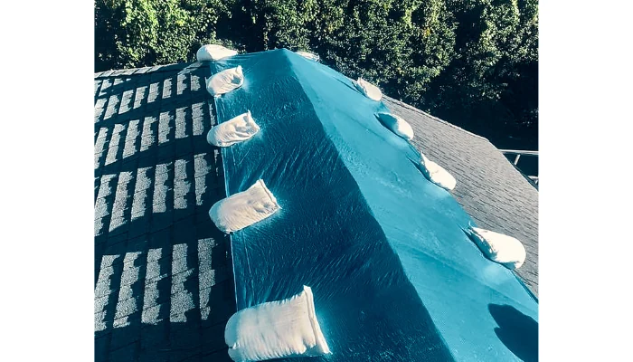 Blue tarp installed with sandbags to represent the keyword what insurance covers.