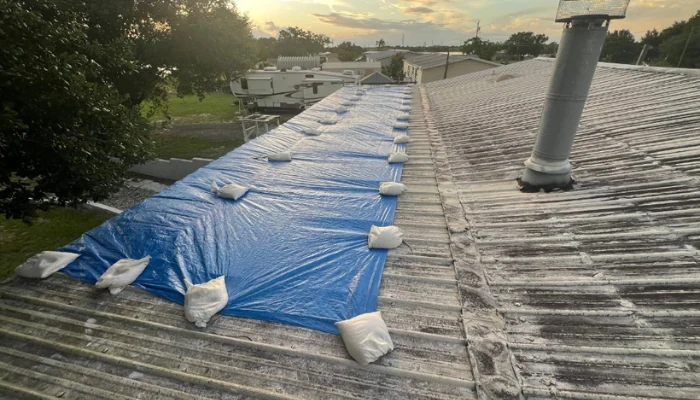 Blue tarp installed with sandbags on a metal roof to represent the keyword blue tarp installed.
