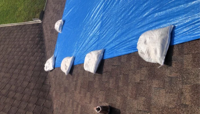 Blue tarp installed on a roof with sandbags to represent the keyword blue tarp on the roof.