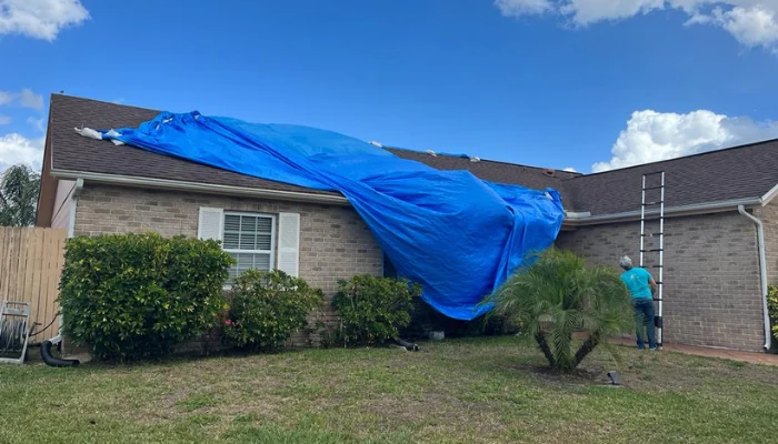Installing a blue tarp on a house to represent the keyword roof emergency for my home.