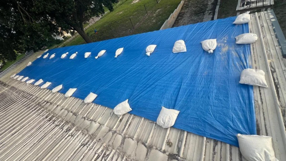 Blue tarp installed with sandbags on a roof to represent the keyword roof water leakage solutions.