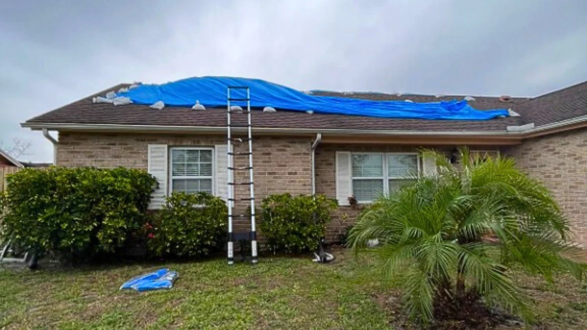 Installing a blue tarp on a house to represent the keyword what can I use to cover a leaking roof.