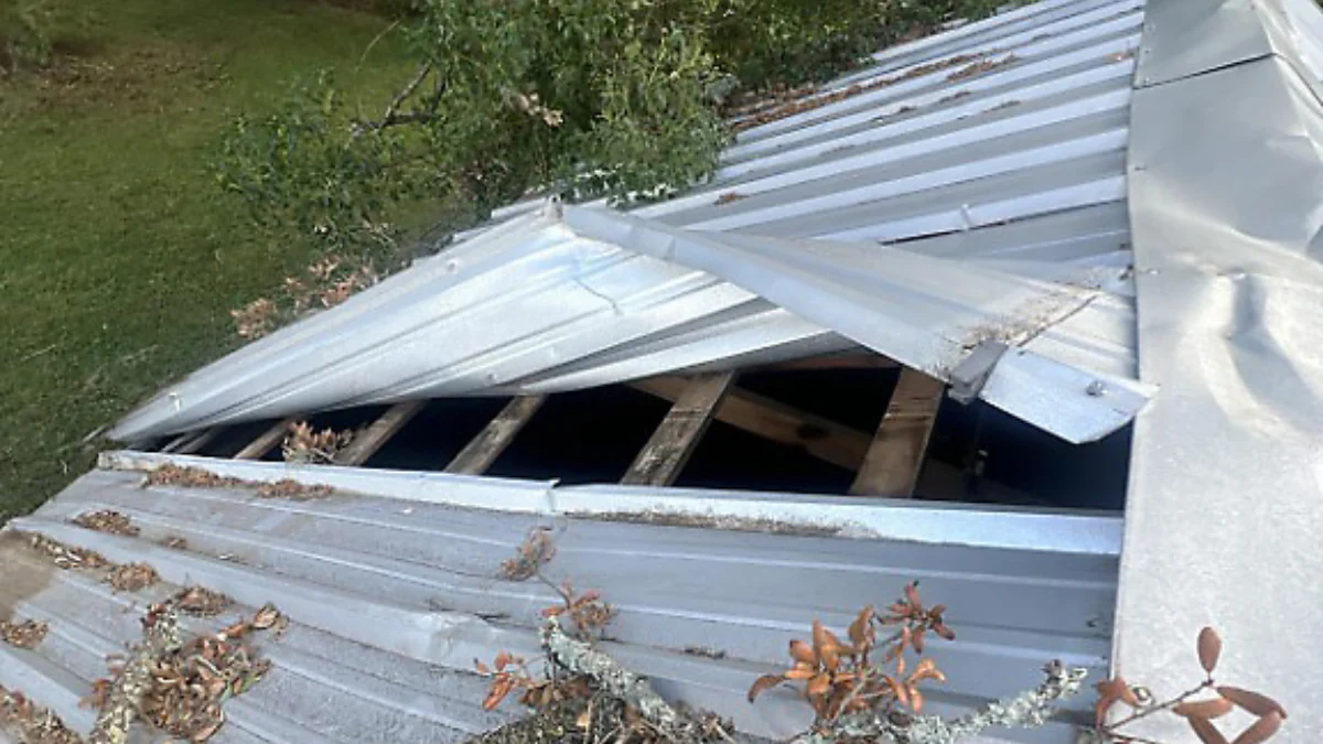 Metal roof with storm damage to represent the keyword what do I do if I have a roof emergency for my home.
