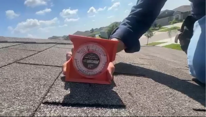 Man taking measurements on a roof during the day to represent the keyword how to replace shingles on a roof.