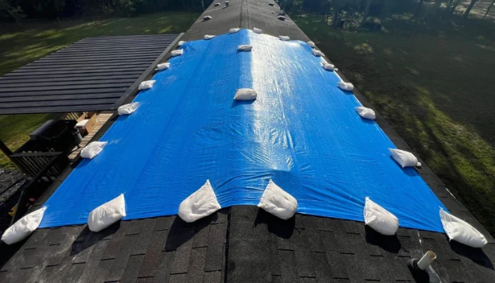 Blue tarp installed with sandbags to represent the keyword tarp installation near me.
