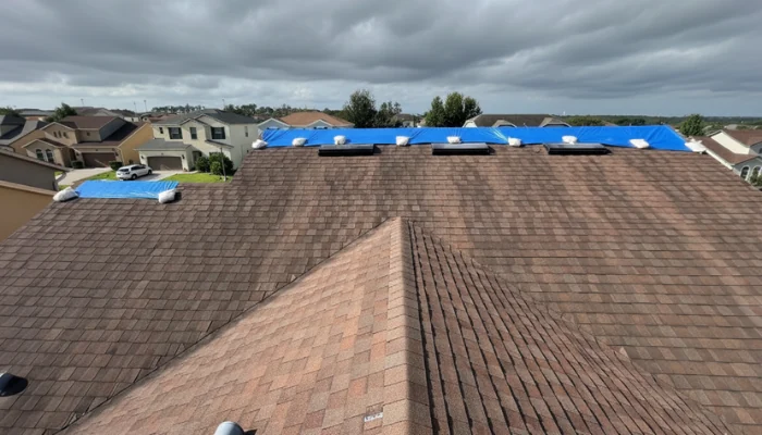 Roof with blue tarp installed with sandbags to represent the keyword emergency roof leak repair.