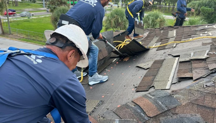 Crew working on roofing, removing shingles to represent the keyword reroofing over asphalt shingles.