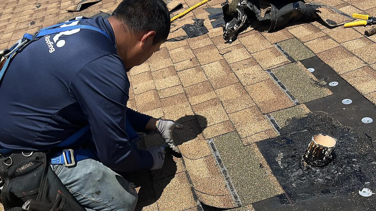Man repairing a roof, next to a pipe to represent the keyword roof replacement.