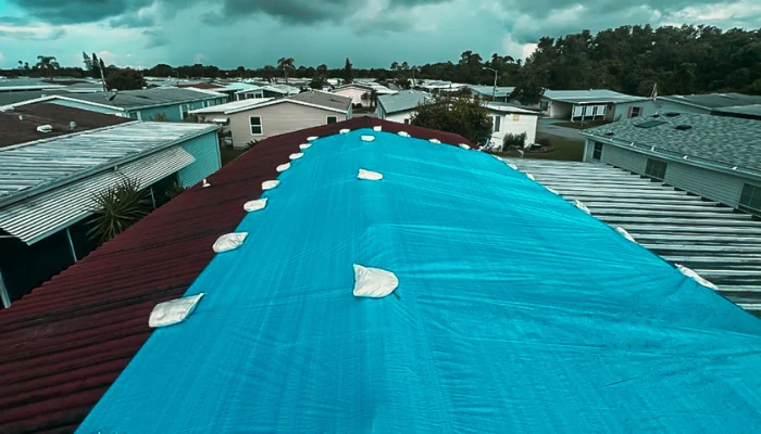 Blue tarp installed on roof with sandbags to represent the keyword emergency roof tarp installation.