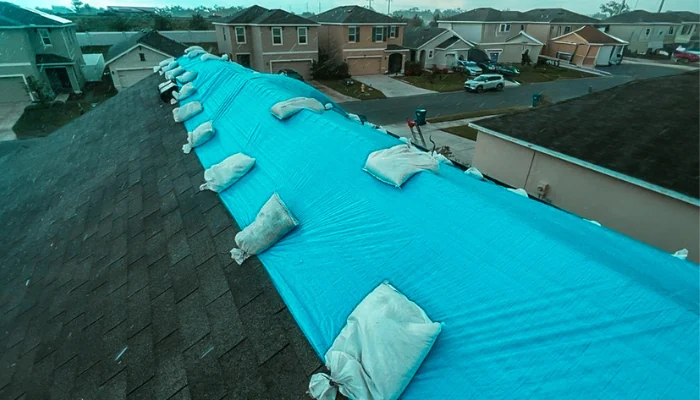 Blue tarp installed with sandbags on a roof to represent the keyword emergency roof tarp.