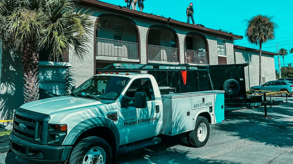 Walking parked in front of a building with men moving on the roof to represent the keyword licensed roofer orlando.