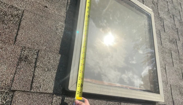 Skylight being measured on a roof to represent the keyword blue tarp cost.