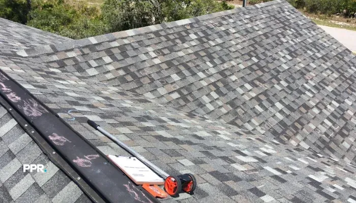 Close-up of a shingle roof marked with chalk, showing areas of damage identified during what is a roof inspection.