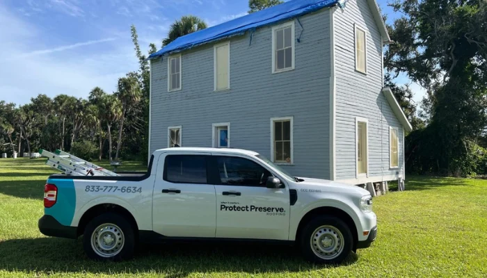 Truck with the company logo parked on a lawn to represent the keyword professional roofer.