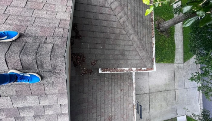 Man on a shingle roof to represent the keyword roof tarp maintance.