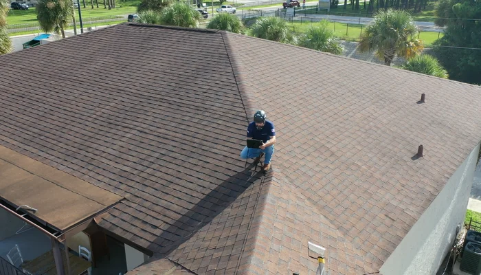 Shingle roof photographed from above with a man repairing it to represent the keyword shingle roof maintance.