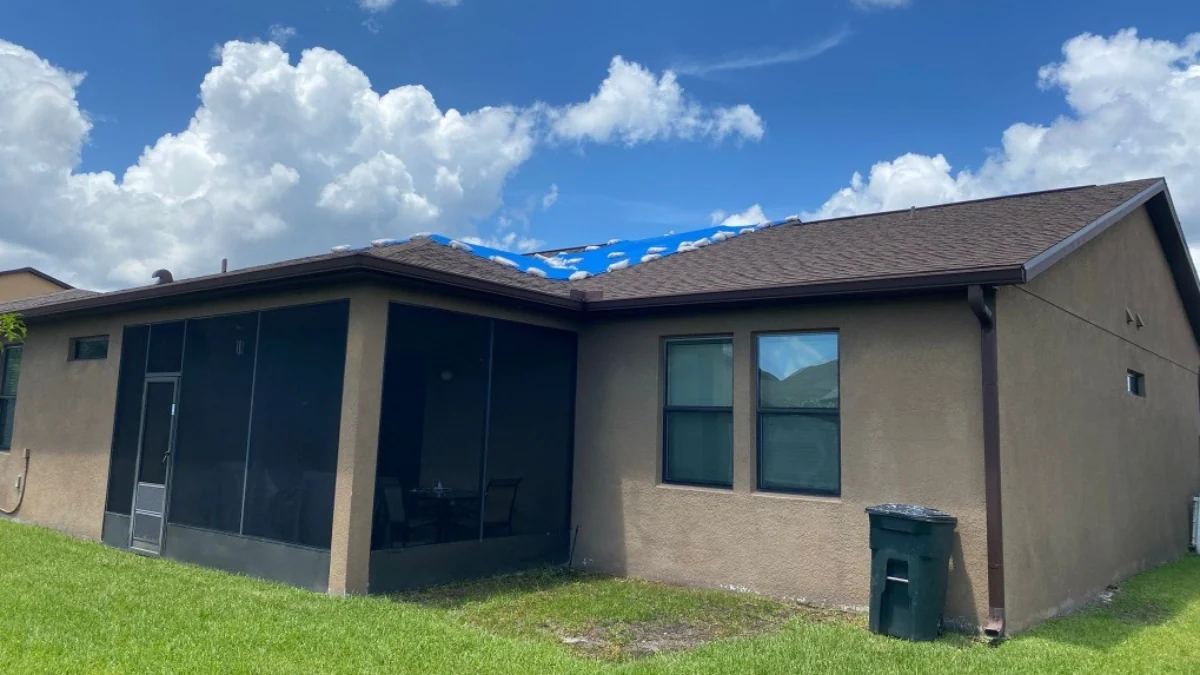 House with blue tarp installed with sandbags to represent the keyword what size tarp do i need for my roof.