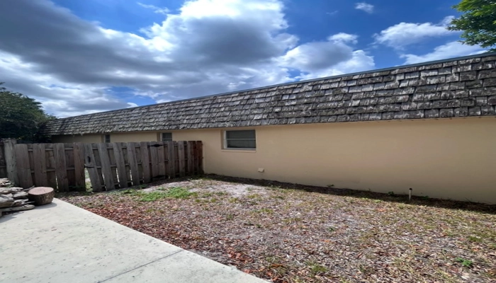 A long side view of a weathered shingle roof with visible fading and age spots, providing a visual reference for homeowners asking "how old is my roof" based on surface condition.