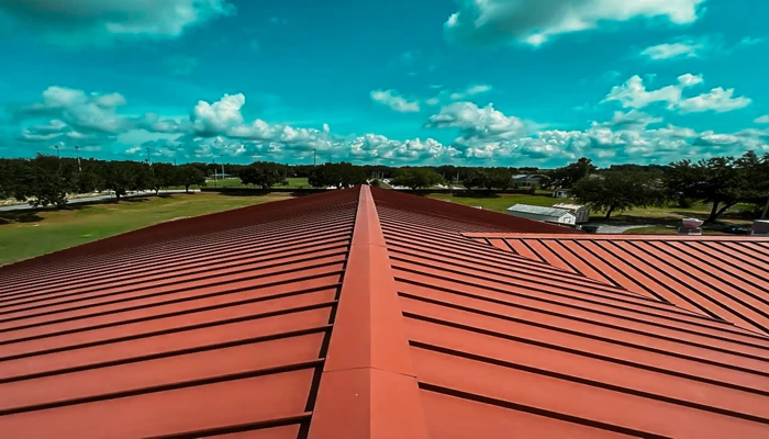A team of contractors finishing the installation of a bright red metal roof on a sunny day, demonstrating the popularity and cooling benefits of metal roofing in Florida.